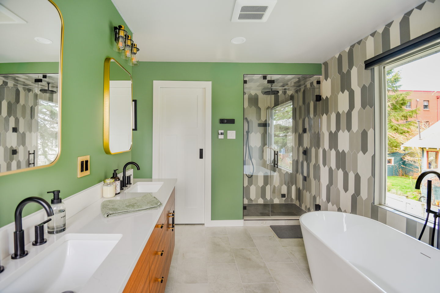 A Ballard primary bathroom with a freestanding tub and green walls