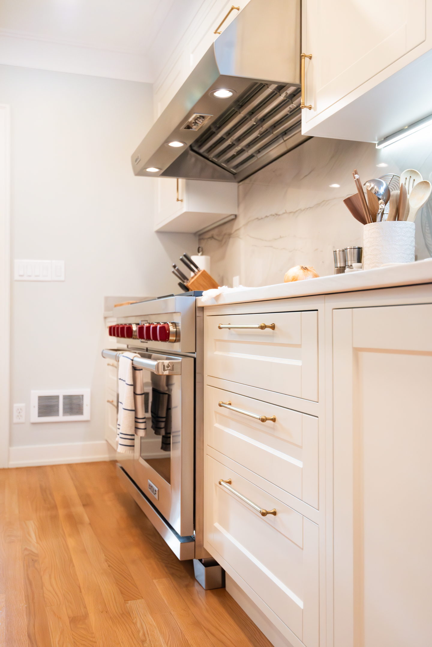 White kitchen cabinetry with an integrated hood and warm wood shelving