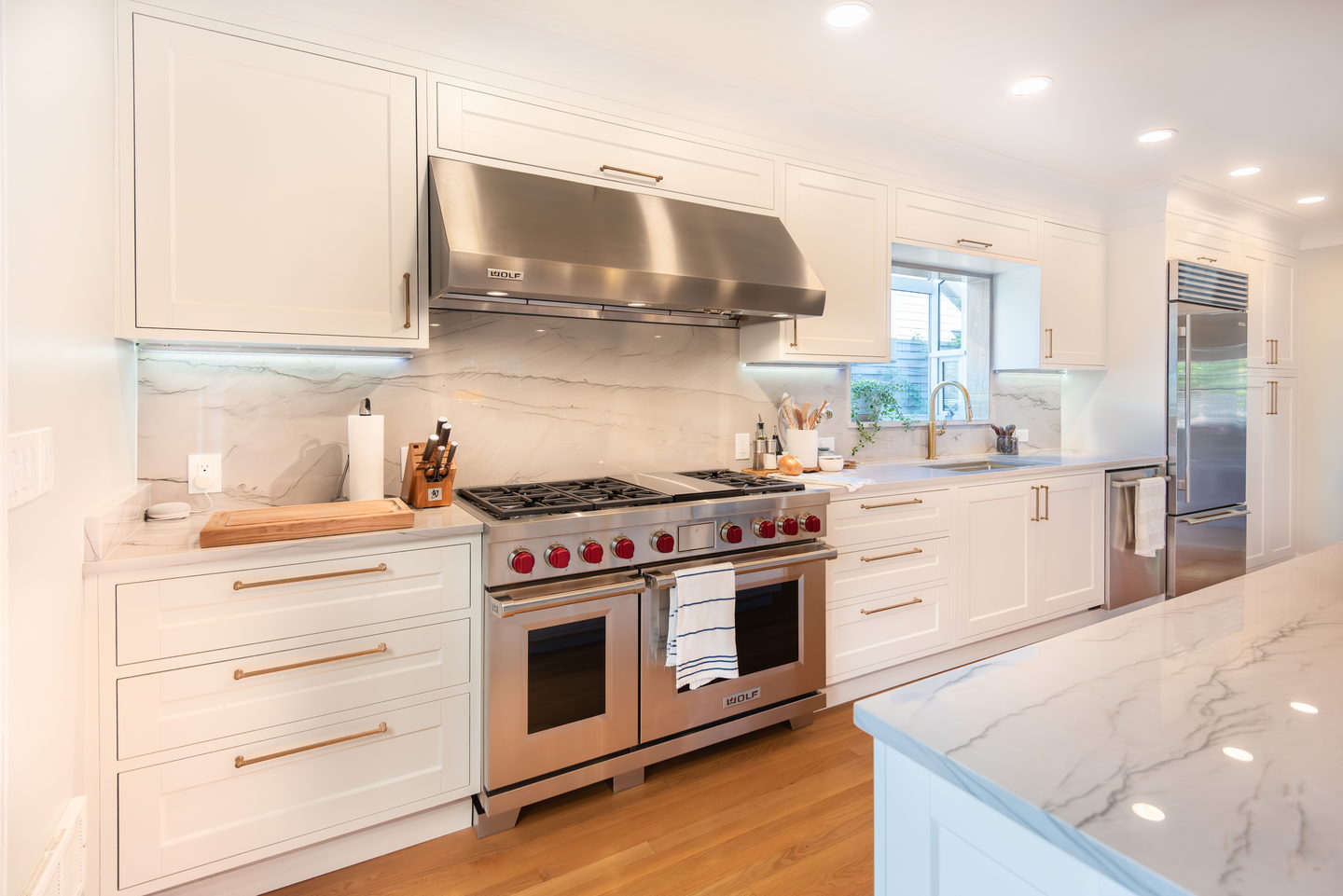A finished kitchen range wall in marble with open shelving and a stainless range