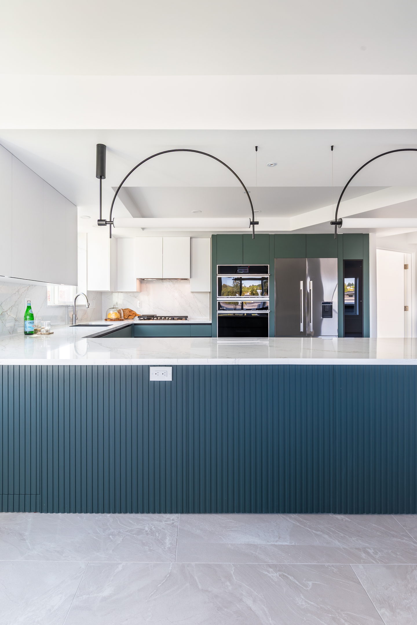 A Kirkland condo kitchen in matte deep green with slim black arched pendant lights