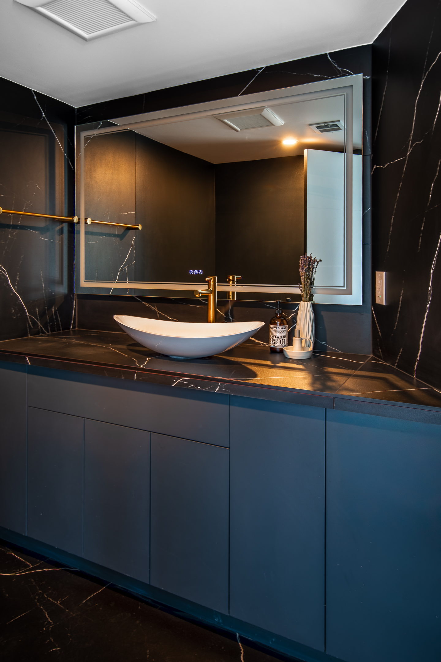 A dark stone bathroom with a green vanity and brass fittings in the Kirkland condominium
