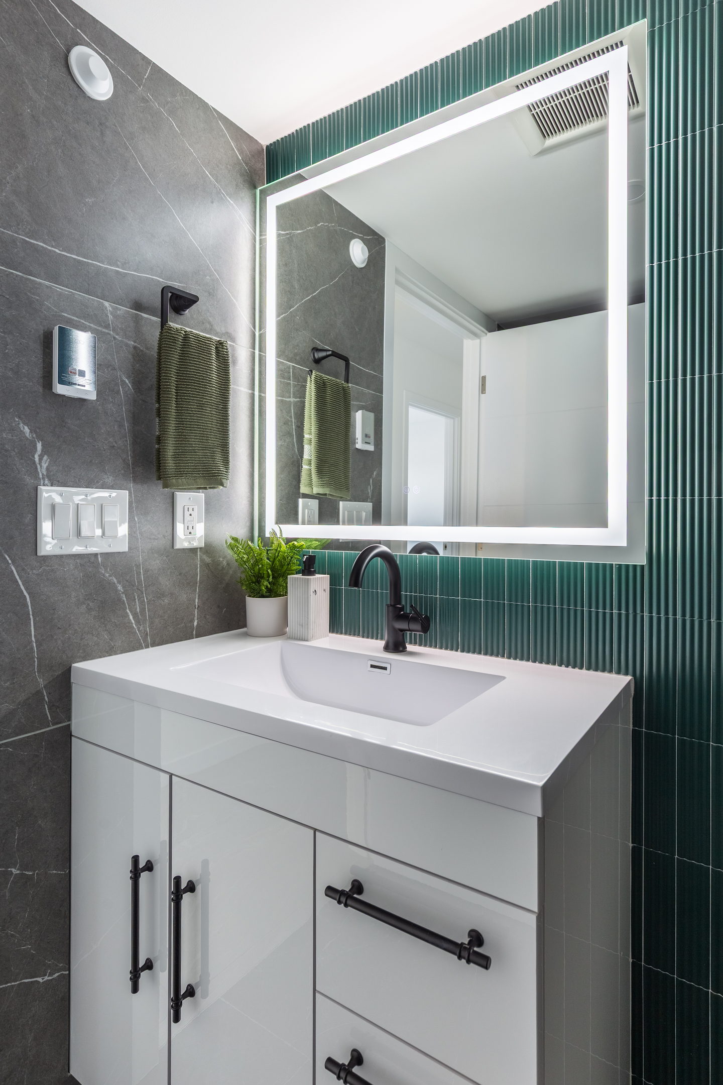 Vertically fluted green tile behind a white vanity