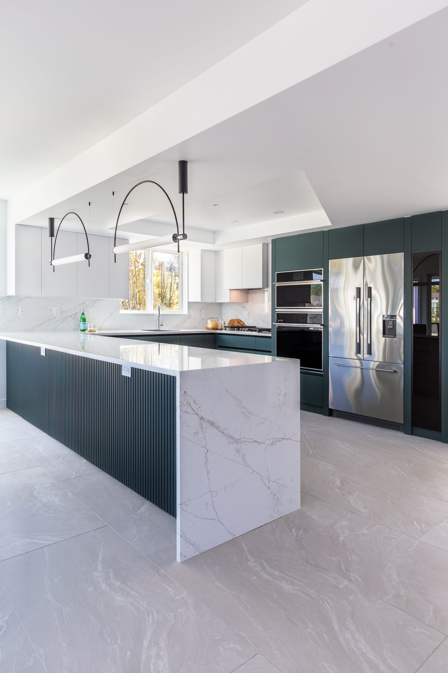 A fluted deep green kitchen island with a thick marble waterfall top