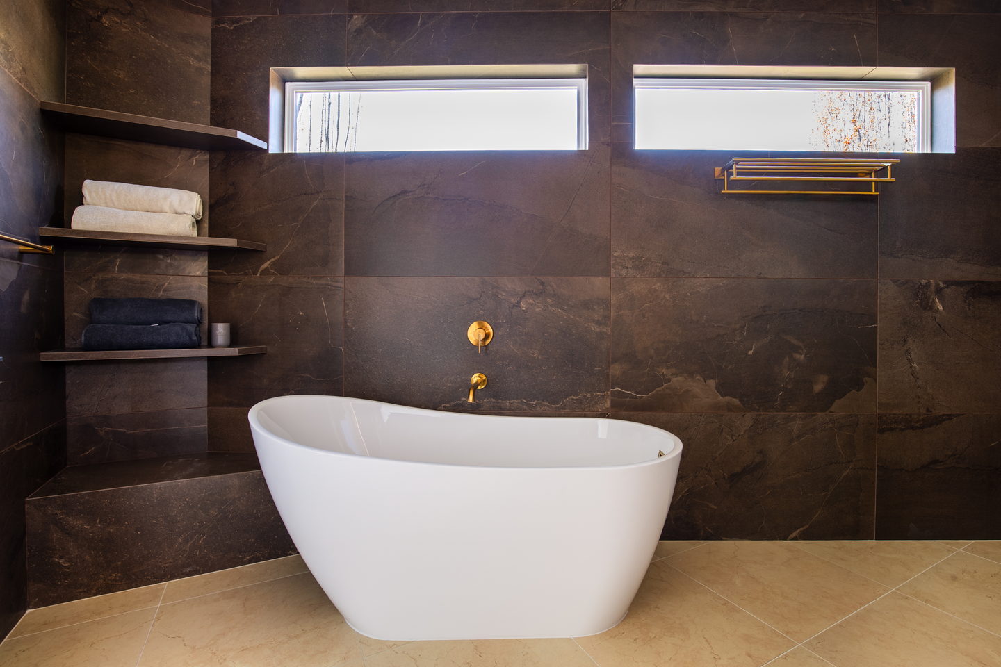 A freestanding tub against a wall of dark veined stone