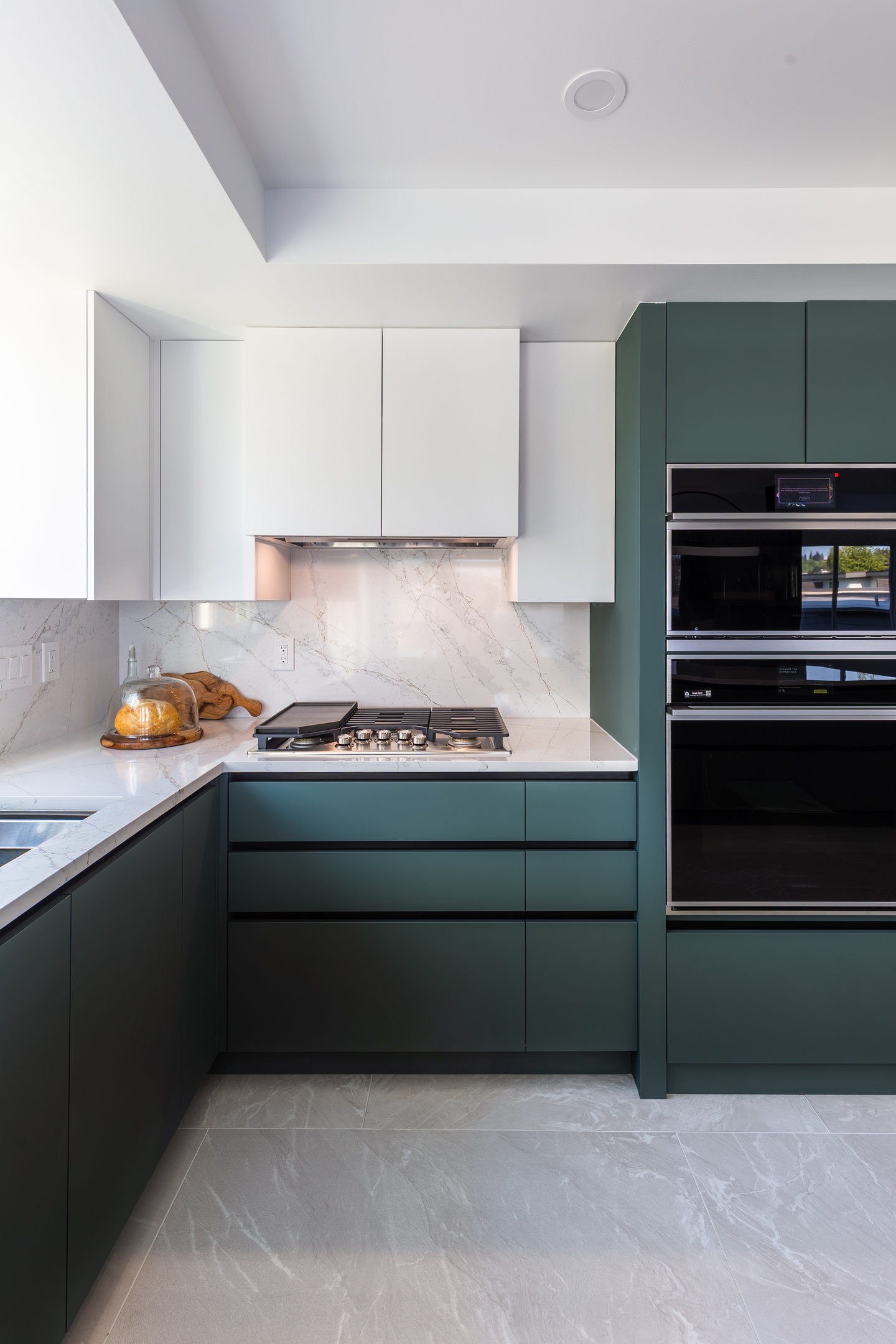 White wall cabinets over green base units beside the oven tower