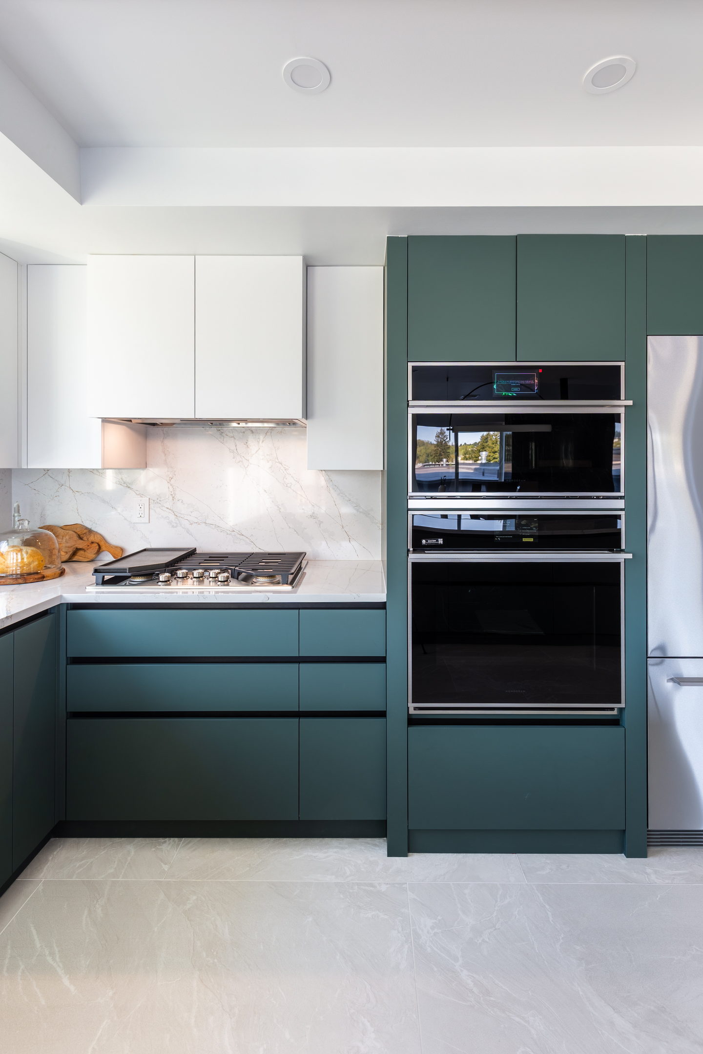 Marble carried up behind the hob, between green cabinetry and the ovens