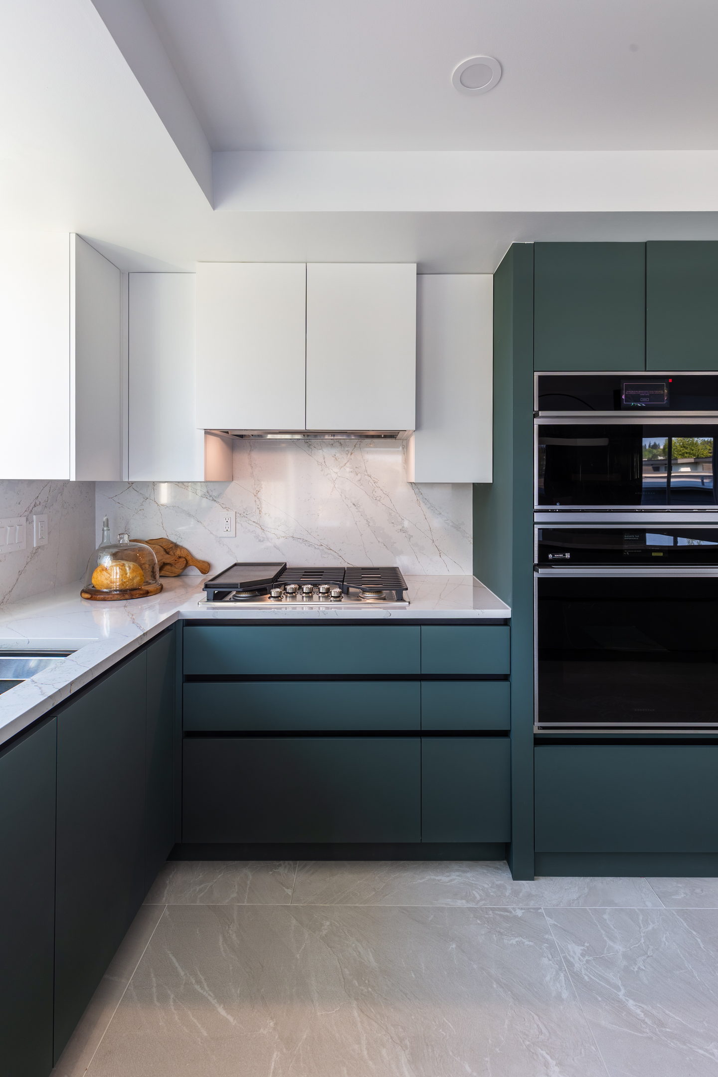 The corner of the kitchen where the green units meet the marble