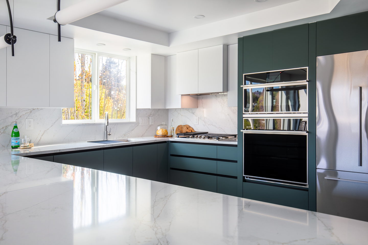 The long run of green base units under a window, with a marble counter
