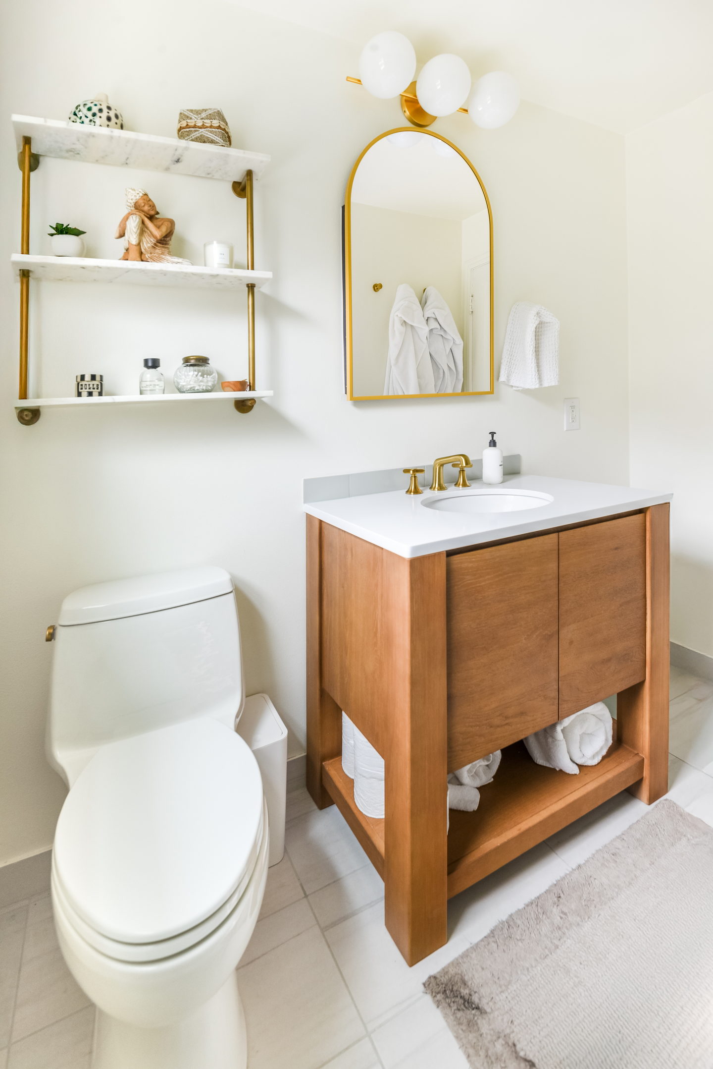 A small Magnolia bathroom in walnut, marble and brass with an arched mirror