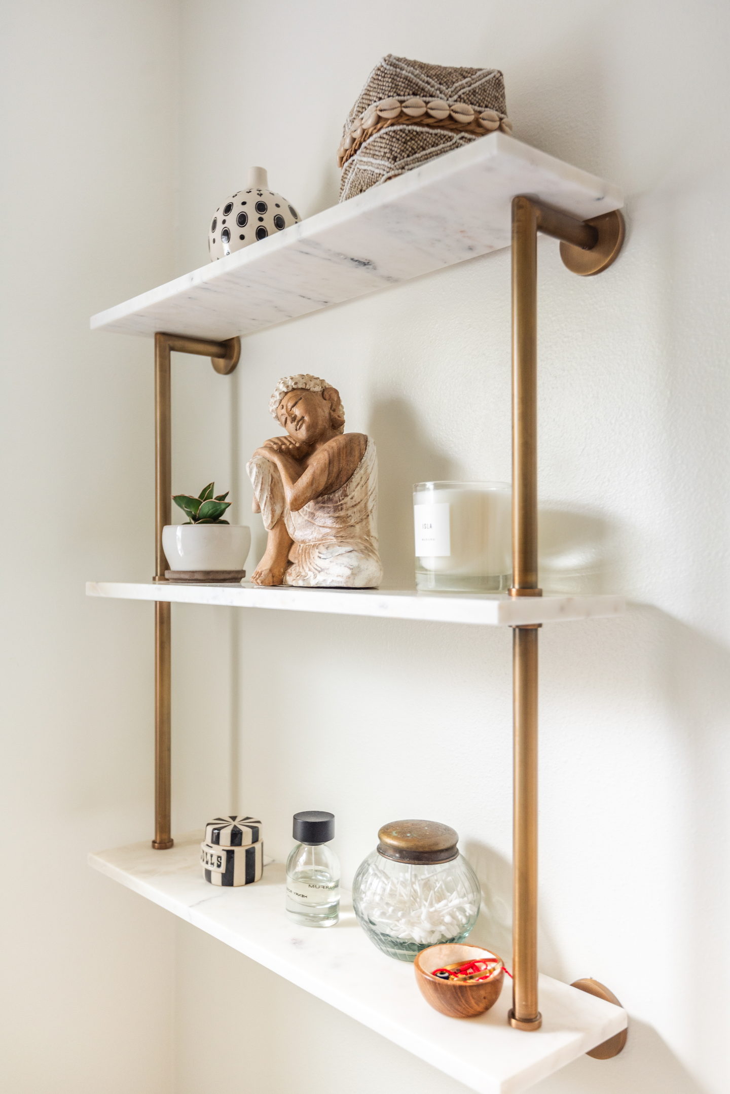 Open marble shelves on slim brass brackets holding small objects
