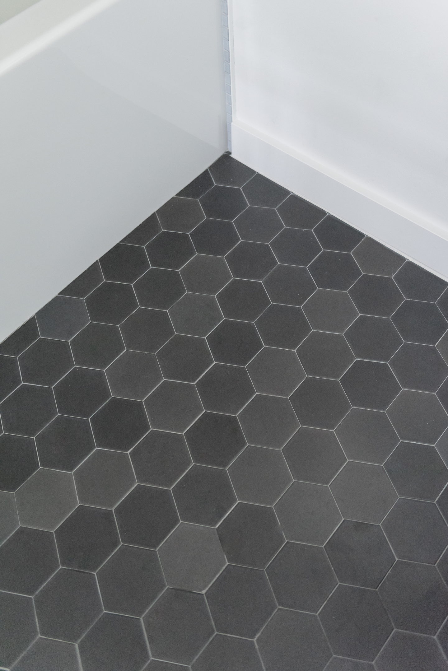 A black hexagonal tiled floor meeting a white baseboard