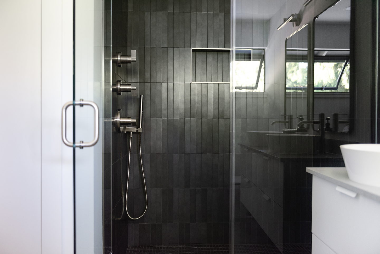 The full bathroom with glass shower, vanity and mirrors seen from the door