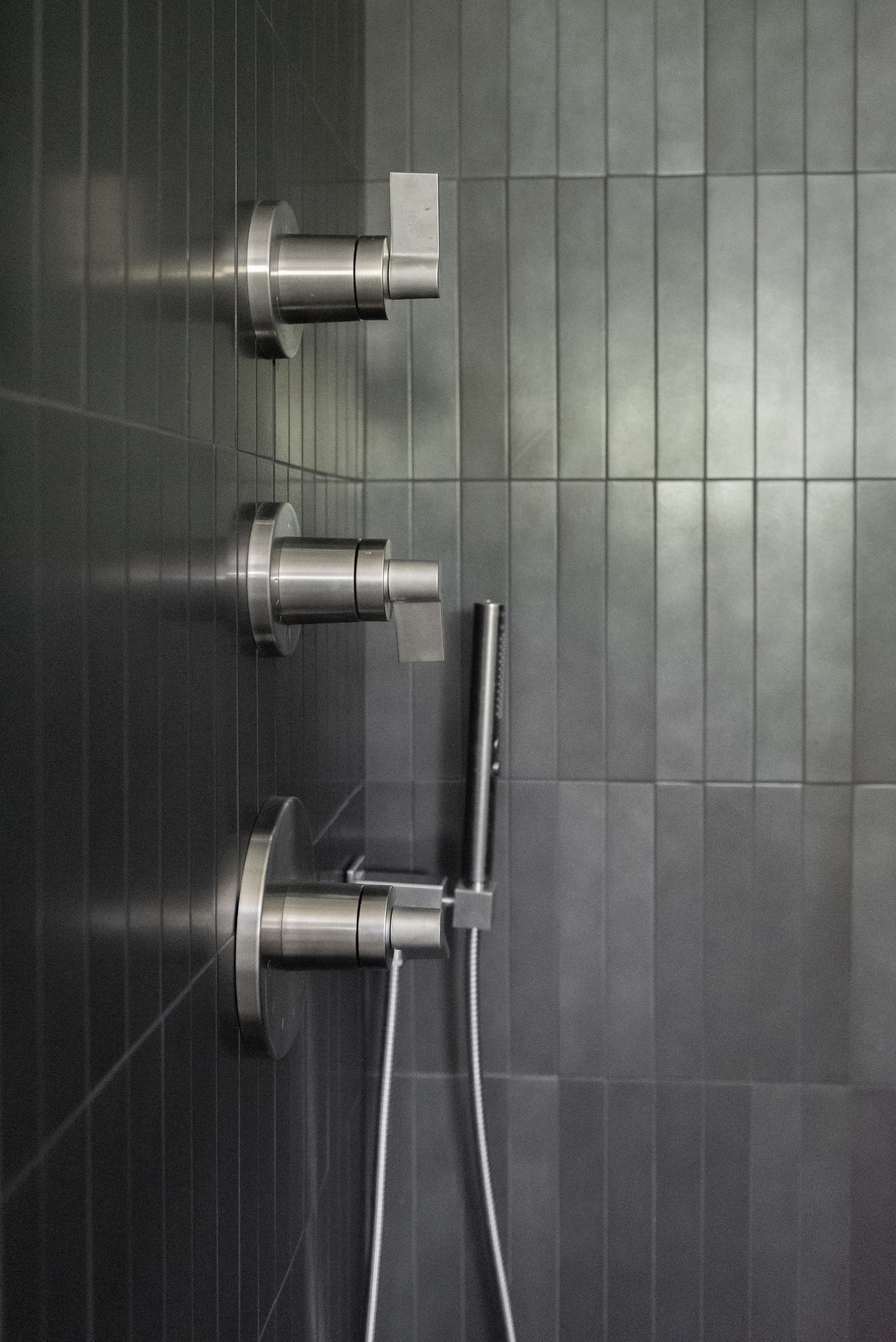 Close view of the stainless shower valves on the black tile