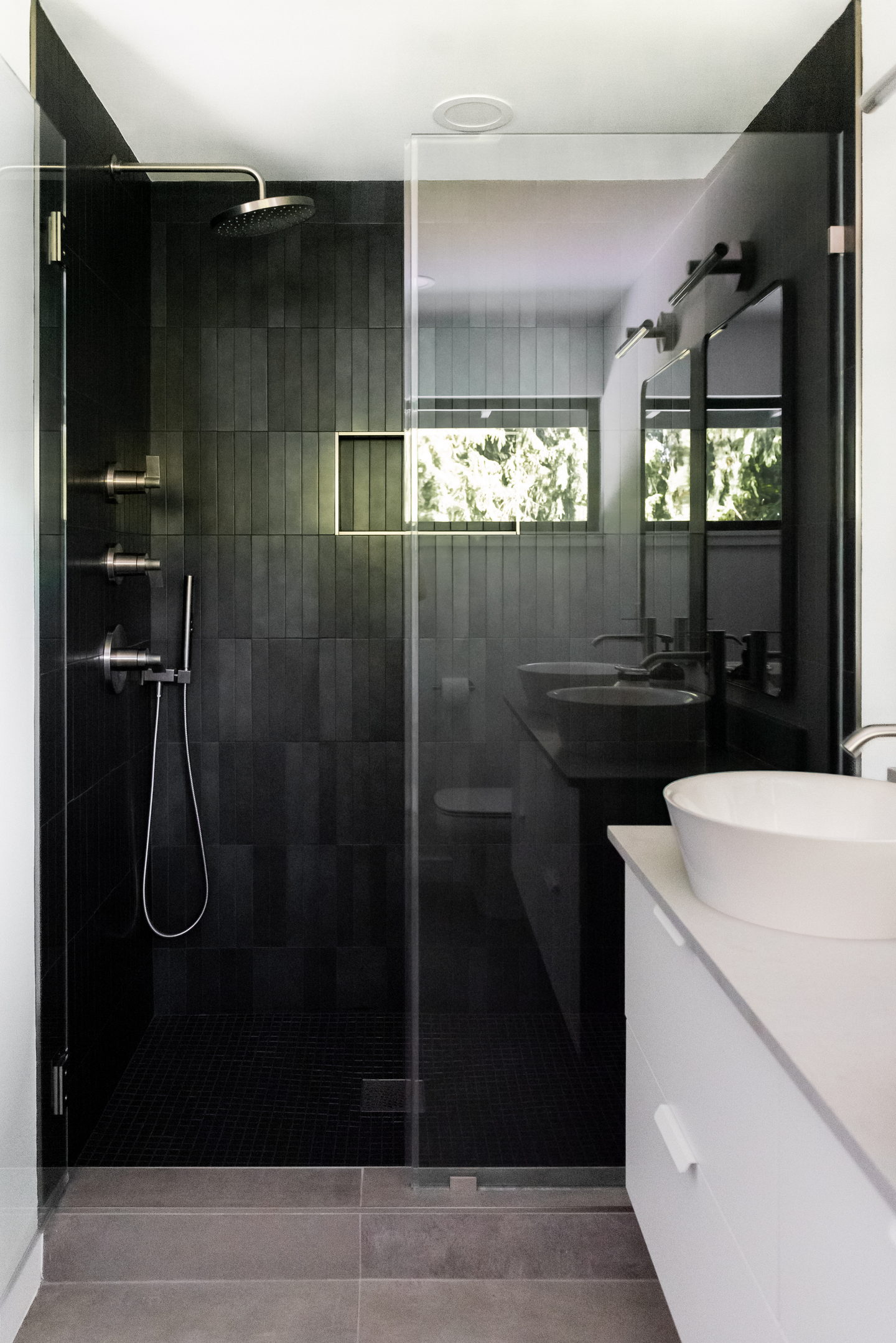 Looking out of the black shower towards the vanity and the window