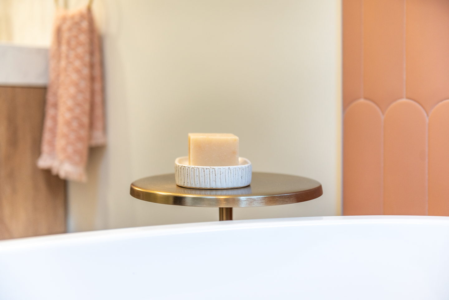 Terracotta arched tile behind a freestanding tub with a brass floor-standing faucet