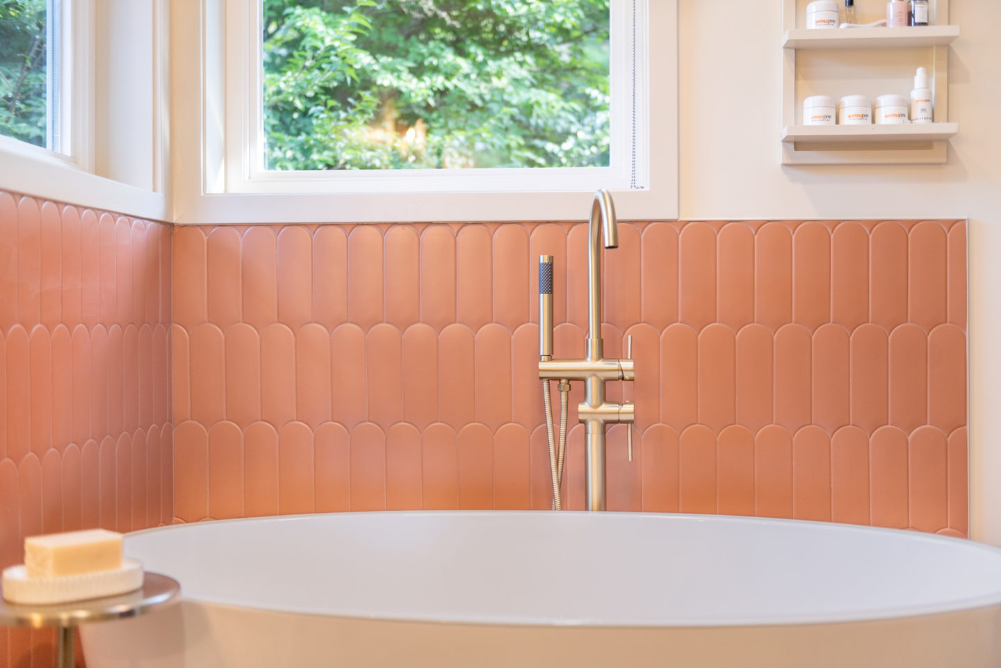 Scalloped terracotta tile behind the tub, with a brass faucet