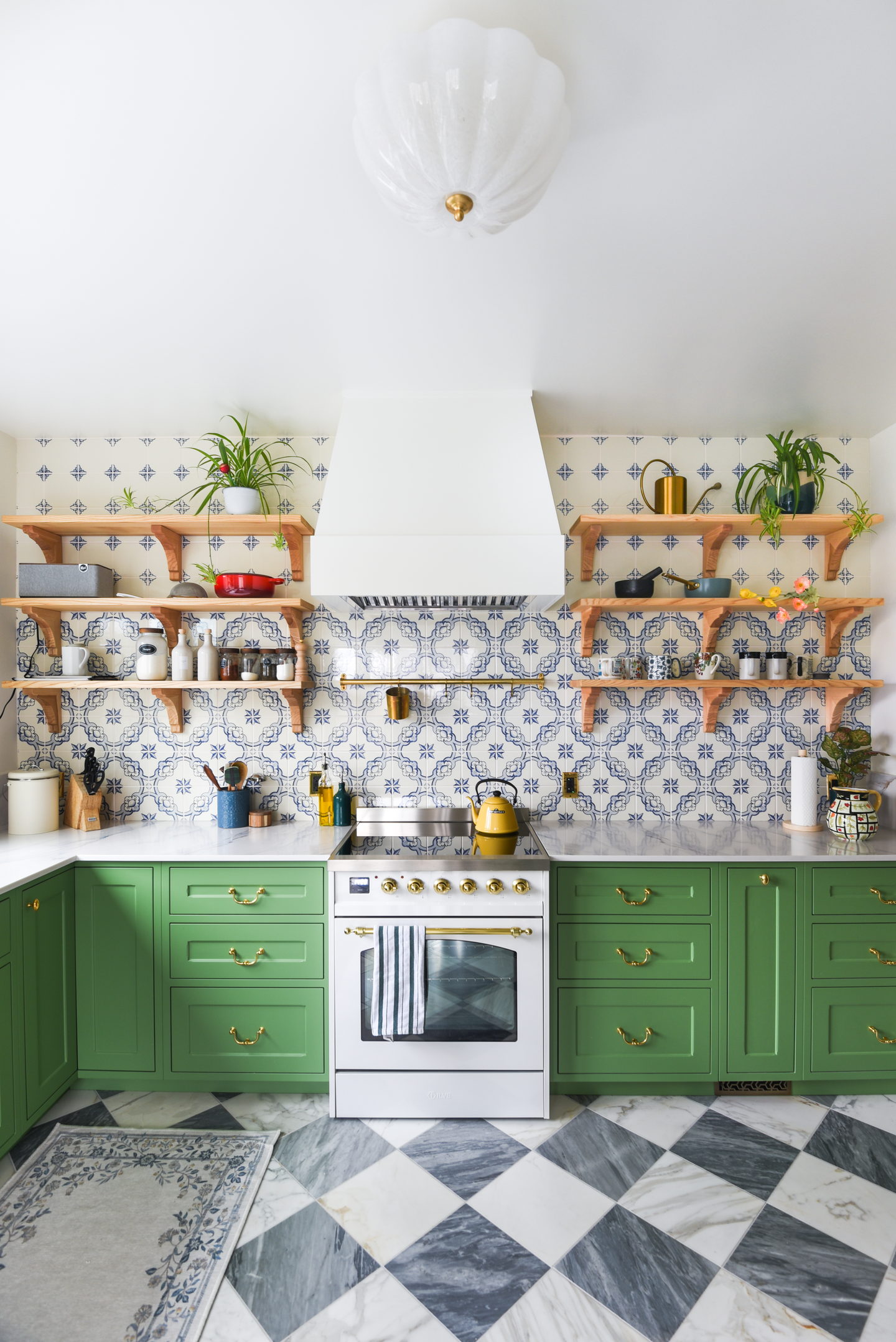 Green painted cabinetry with brass cup pulls and open shelving above