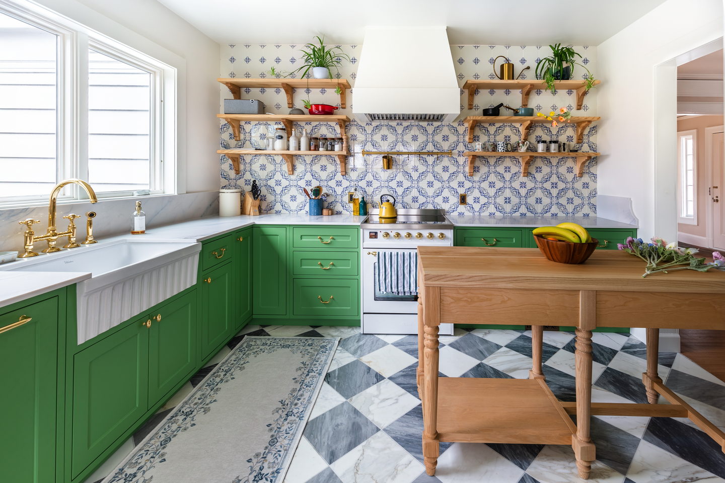 The period kitchen from the doorway: green cabinetry, patterned tile and a wood island