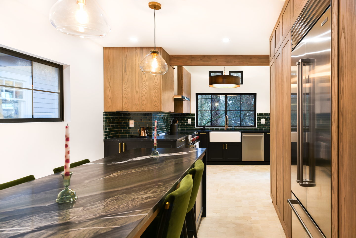 A University District kitchen with white oak cabinets, black lowers, a dark stone island and green zellige tile