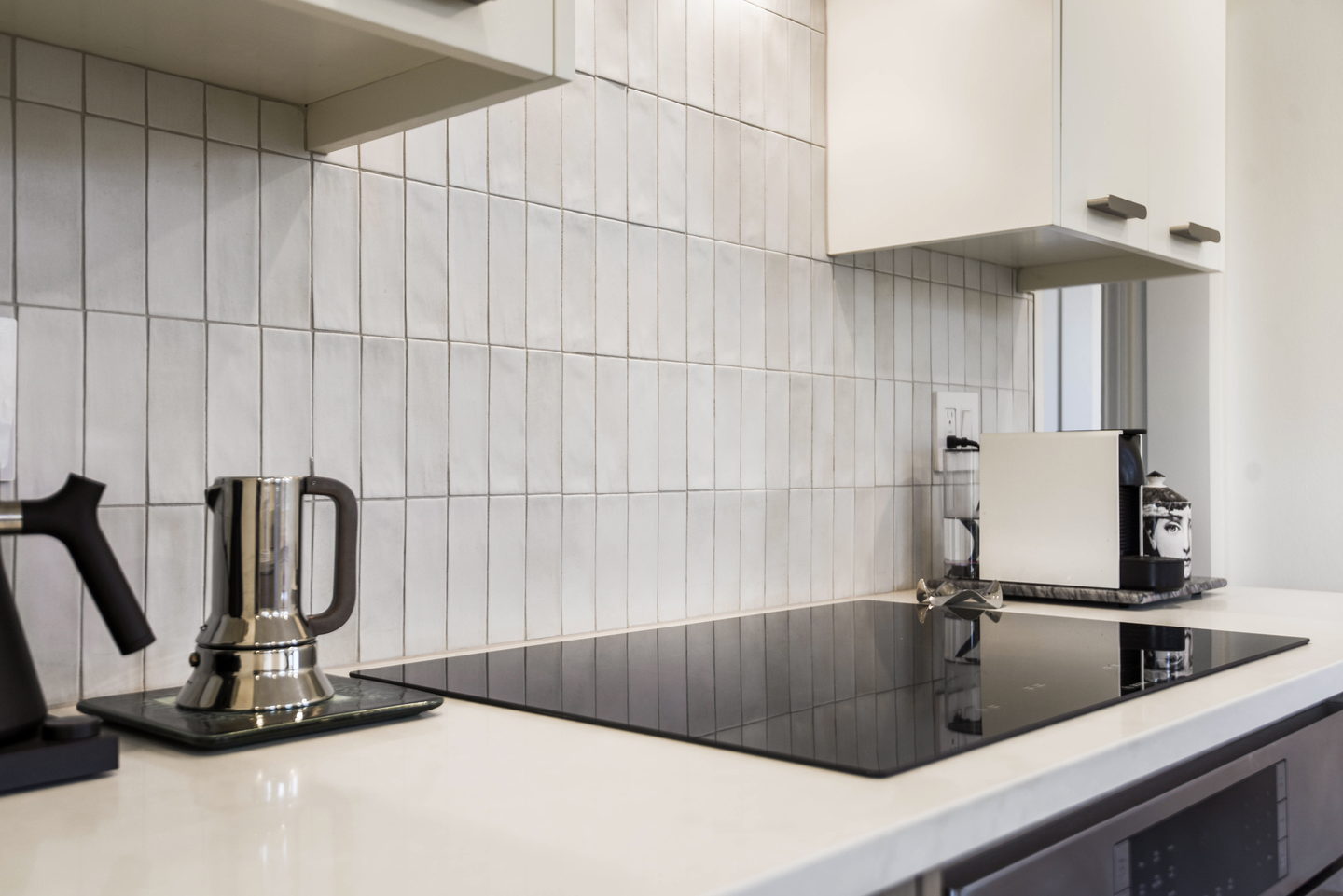 A white tiled range wall with an induction hob and a slim extractor
