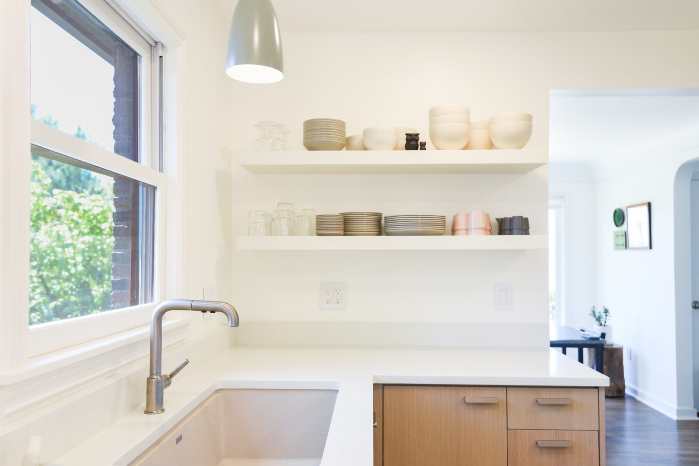 Two short open shelves over a sink with a window beyond